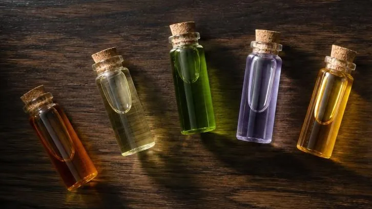 Five vials of colored terpene oils arranged on dark walnut, representing the entourage effect
